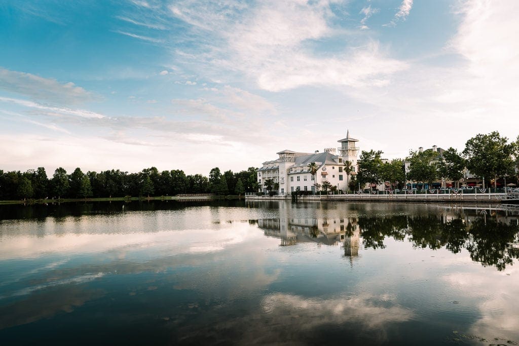 A picturesque exterior view of the Bohemian Hotel Celebration, with its classic Southern-style architecture and sweeping verandas set against the tranquil blue waters of the lake.