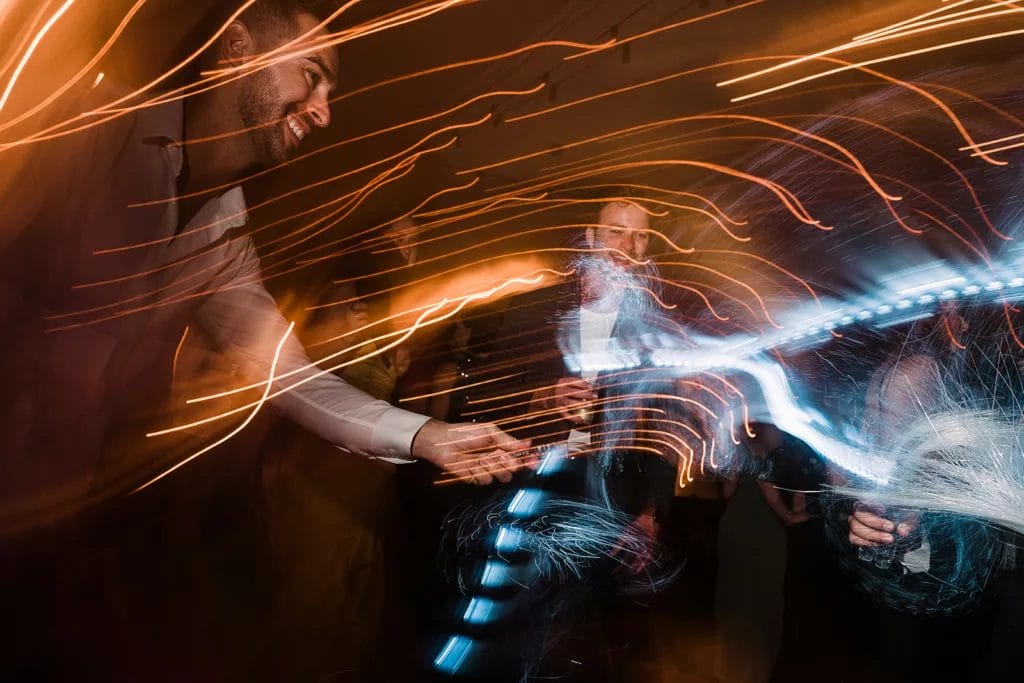 Guests at a wedding playing with led ribbon wands at reception
