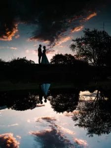 A unique mirrored reflection of a bride and groom from a pond at a wedding.