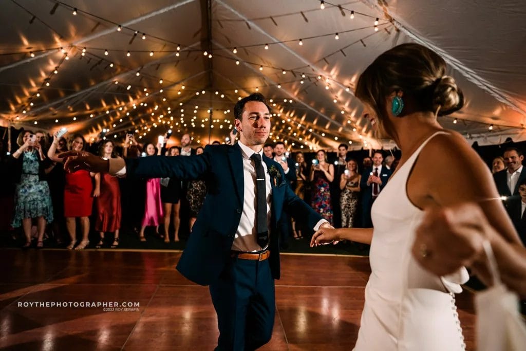 The bride and groom share their first dance at their Sunken Gardens wedding reception, surrounded by guests holding up their phones to capture the moment.