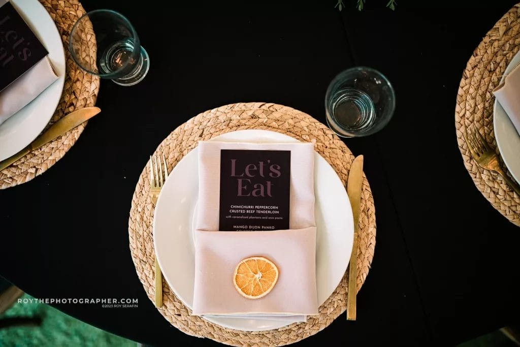 An overhead shot of a wedding reception table setting at Sunken Gardens featuring a "Let's Eat" menu card, adding a personalized touch to the dining experience