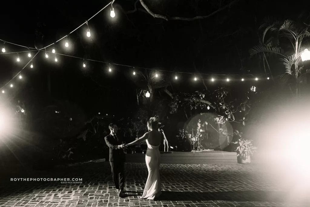 A bride and groom share a dance under the night sky at Sunken Gardens, illuminated by strings of lights, creating a dreamy, romantic wedding scene.