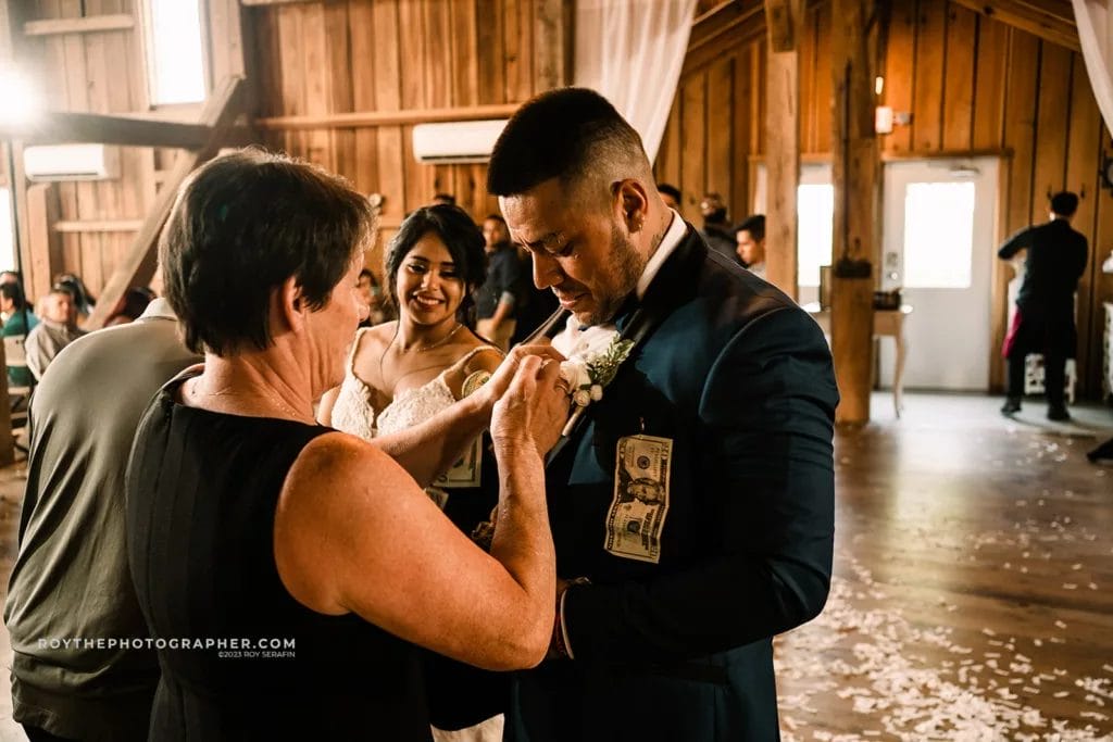 A woman pinning dollars to the grooms seat during a dollar dance at a mexican wedding.